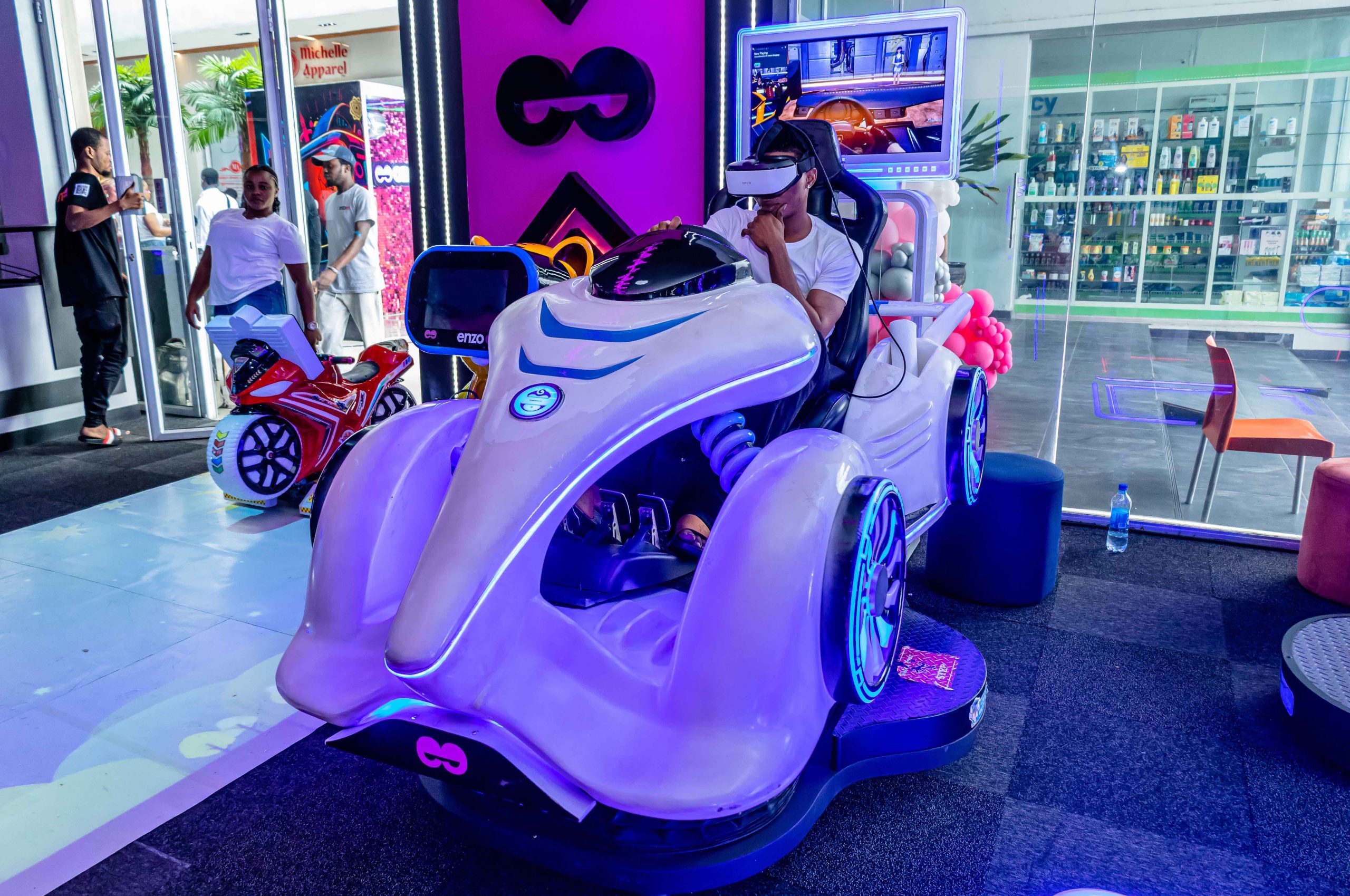 A teen playing a VR game while others watch and laugh.